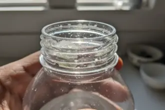 Biofilme garrafa água acumulado no interior e bocal de uma garrafa reutilizável com micro-organismos e lodo invisível.