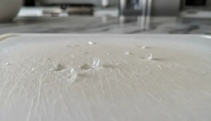 Tábua de corte sintética com ranhuras de uso. Pare de usar tábuas de plástico para evitar a ingestão de microplásticos.