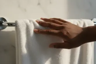 Pessoa segurando toalha no banheiro. Saiba quantos dias usa a mesma toalha de banho para evitar bactérias na pele.